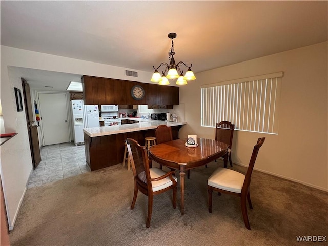 dining room featuring light carpet, baseboards, visible vents, and a notable chandelier