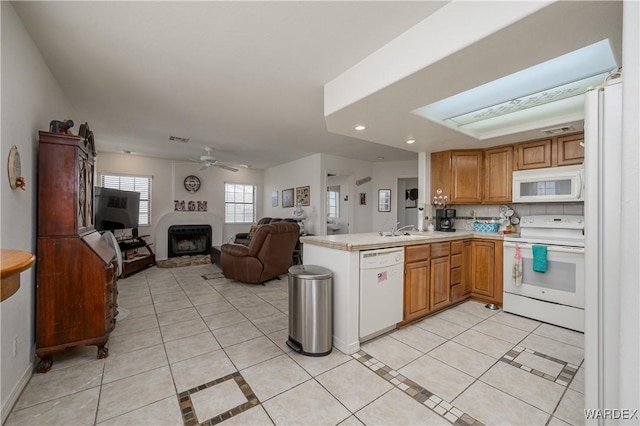 kitchen with light countertops, open floor plan, light tile patterned flooring, white appliances, and a peninsula