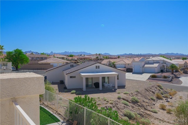 view of front of property with a residential view, a fenced backyard, a mountain view, and stucco siding