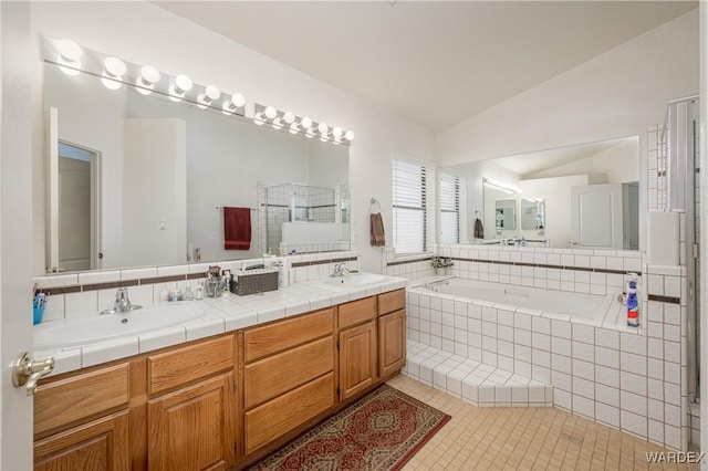 full bath with tile patterned floors, vaulted ceiling, a sink, and double vanity