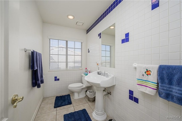 bathroom with toilet, tile patterned flooring, and tile walls