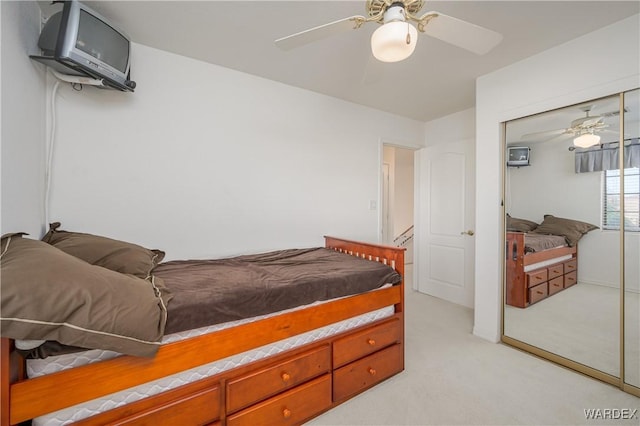 bedroom featuring light carpet, ceiling fan, and a closet