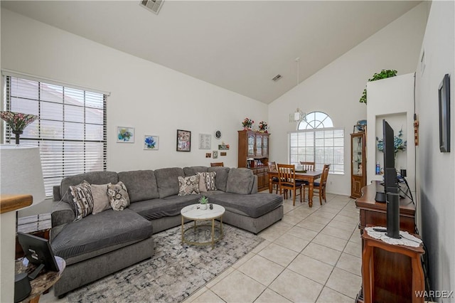 living room featuring light tile patterned floors, visible vents, and high vaulted ceiling