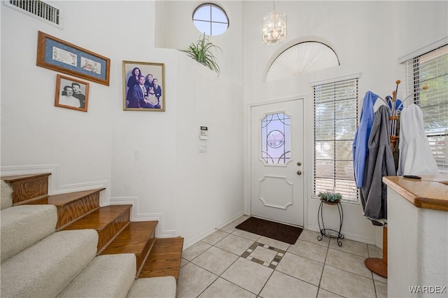 foyer entrance with stairway, light tile patterned flooring, visible vents, and a healthy amount of sunlight