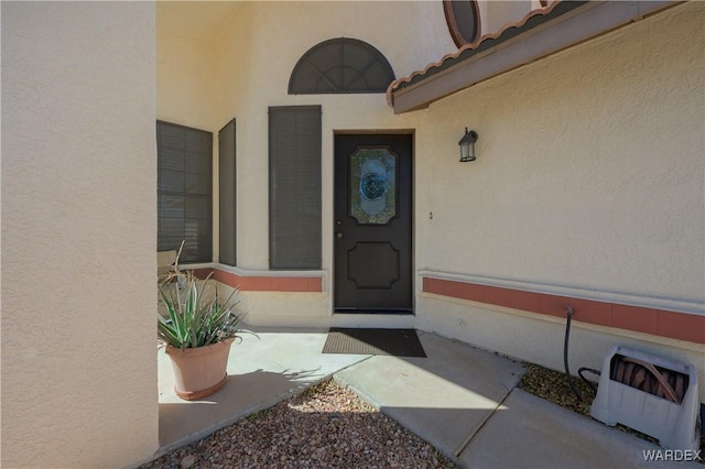 view of exterior entry featuring a tile roof and stucco siding