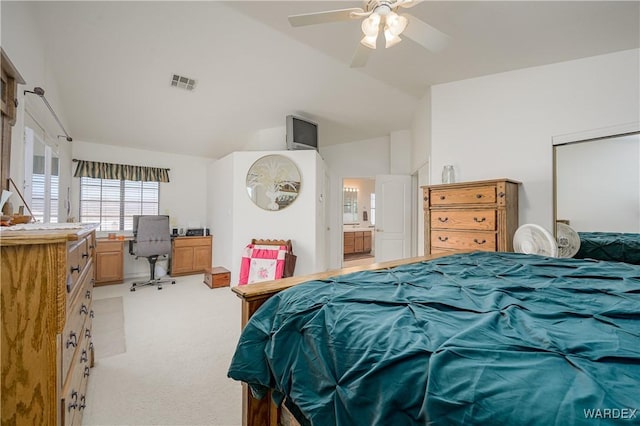 bedroom with visible vents, light colored carpet, ceiling fan, ensuite bathroom, and vaulted ceiling