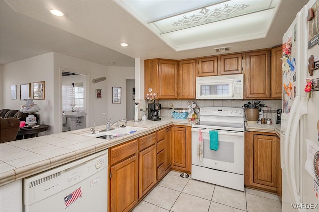 kitchen with tile countertops, tasteful backsplash, visible vents, a sink, and white appliances