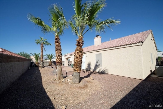 rear view of house with stucco siding, a tiled roof, and a fenced backyard