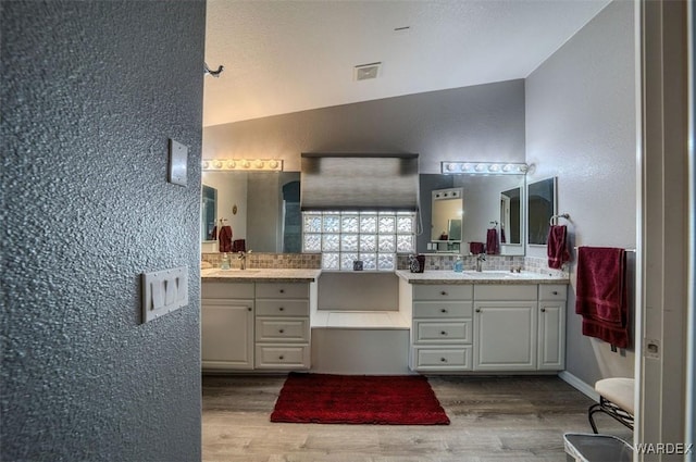 bathroom featuring vanity, vaulted ceiling, and wood finished floors