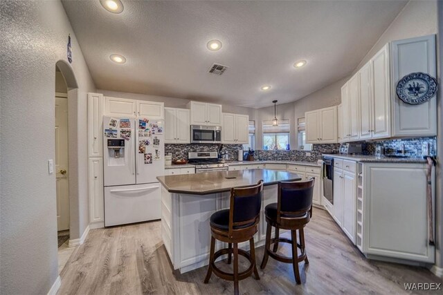 kitchen featuring visible vents, light wood-style flooring, stainless steel appliances, and decorative backsplash