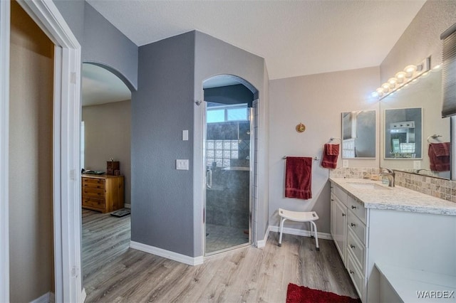 bathroom featuring a stall shower, baseboards, wood finished floors, and vanity