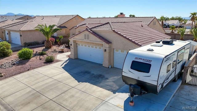 view of front of house featuring concrete driveway, a tile roof, stucco siding, a chimney, and a garage