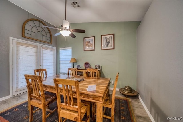 dining room with visible vents, lofted ceiling, baseboards, and wood finished floors