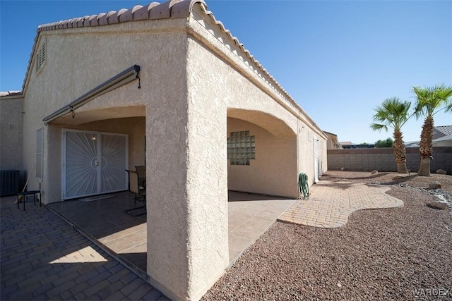 back of property with stucco siding, a tiled roof, a patio, and fence