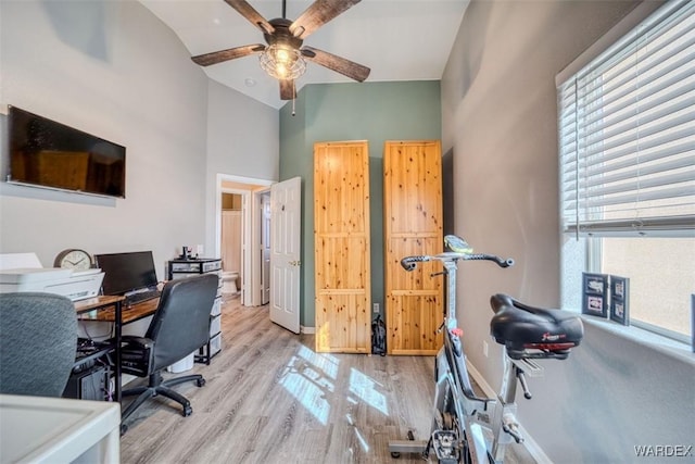 office with baseboards, a ceiling fan, a towering ceiling, and wood finished floors