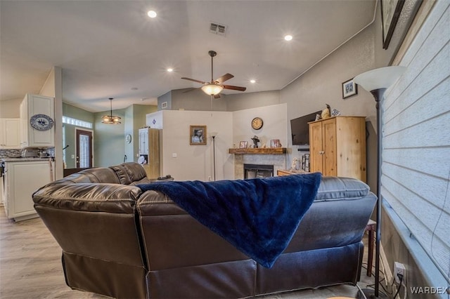 living area with visible vents, ceiling fan, light wood-type flooring, recessed lighting, and a fireplace