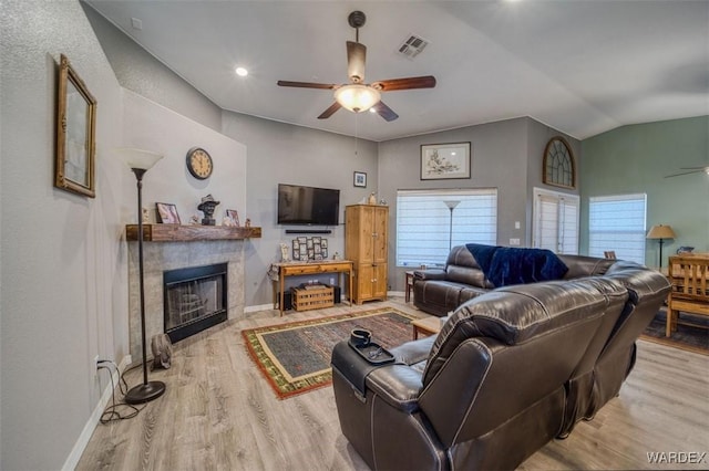 living room featuring visible vents, a tiled fireplace, a ceiling fan, wood finished floors, and vaulted ceiling