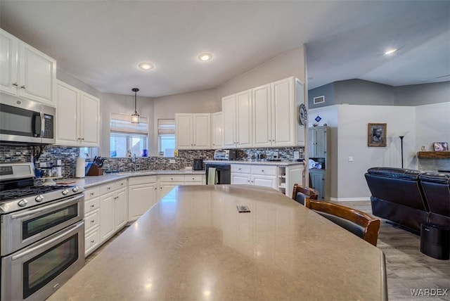 kitchen featuring decorative backsplash, white cabinets, appliances with stainless steel finishes, and a sink