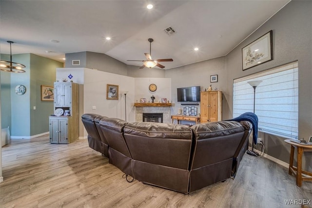 living room with visible vents, a fireplace, lofted ceiling, and light wood-style floors