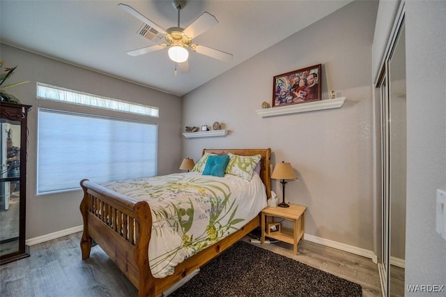 bedroom with wood finished floors, visible vents, baseboards, ceiling fan, and vaulted ceiling