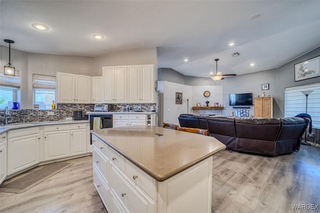 kitchen featuring backsplash, open floor plan, light wood-style flooring, white cabinetry, and a sink