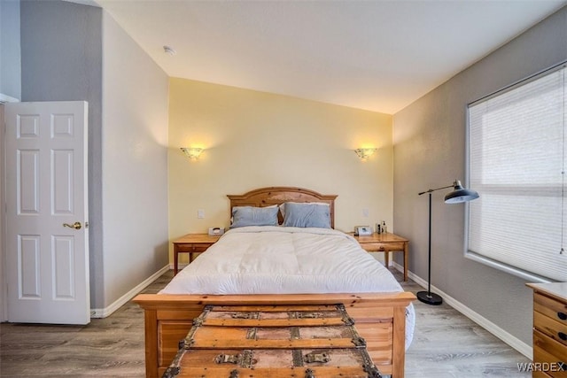 bedroom with lofted ceiling, baseboards, and wood finished floors