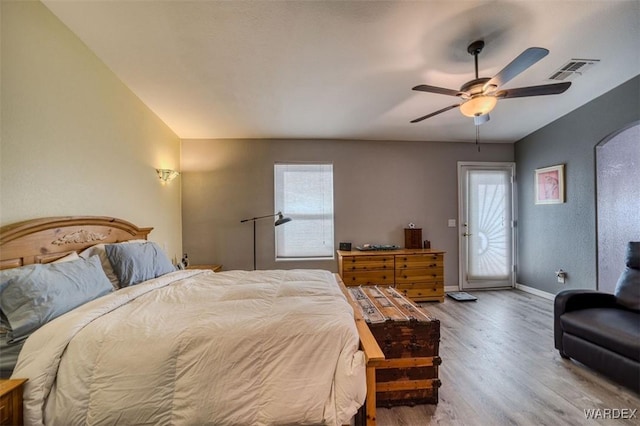 bedroom featuring visible vents, ceiling fan, baseboards, wood finished floors, and arched walkways