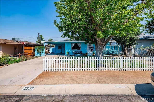 view of front of property featuring driveway, a fenced front yard, and an attached carport