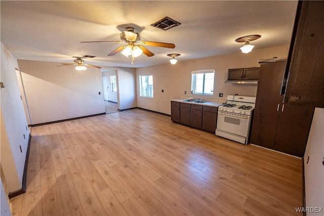 kitchen featuring light wood-style floors, light countertops, white gas stove, and dark brown cabinets