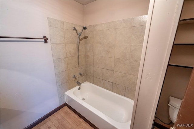 bathroom featuring shower / washtub combination, baseboards, toilet, and wood finished floors