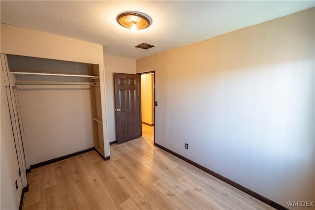 unfurnished bedroom featuring a closet, light wood-type flooring, visible vents, and baseboards