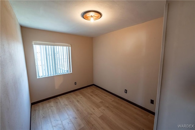 spare room featuring baseboards and light wood finished floors