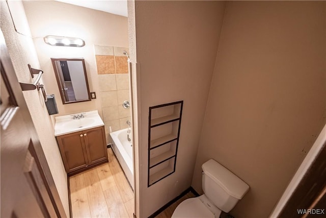 full bath with toilet, a washtub, wood finished floors, and vanity