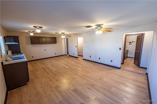 living room featuring a ceiling fan, light wood-type flooring, visible vents, and baseboards