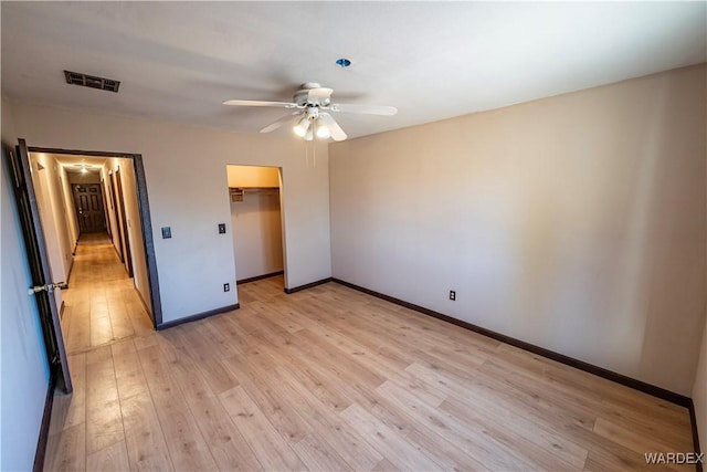 unfurnished bedroom featuring a closet, visible vents, light wood-style floors, ceiling fan, and baseboards