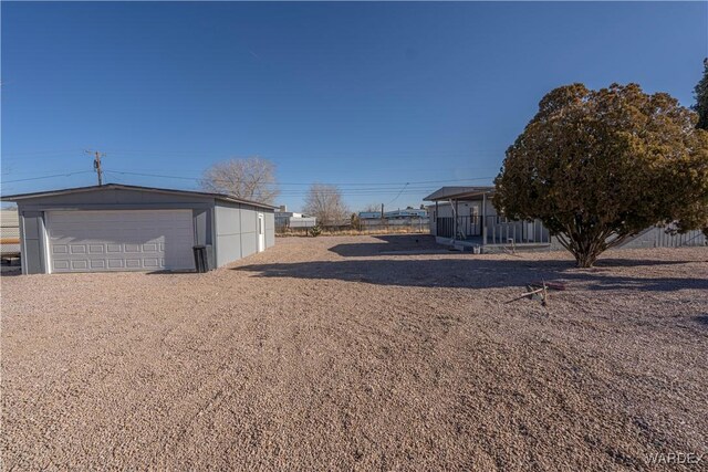 view of yard with a detached garage, fence, and an outdoor structure