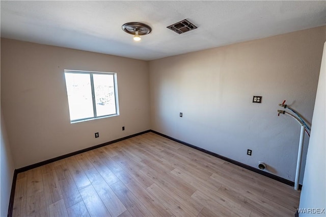 empty room featuring light wood-type flooring, baseboards, and visible vents