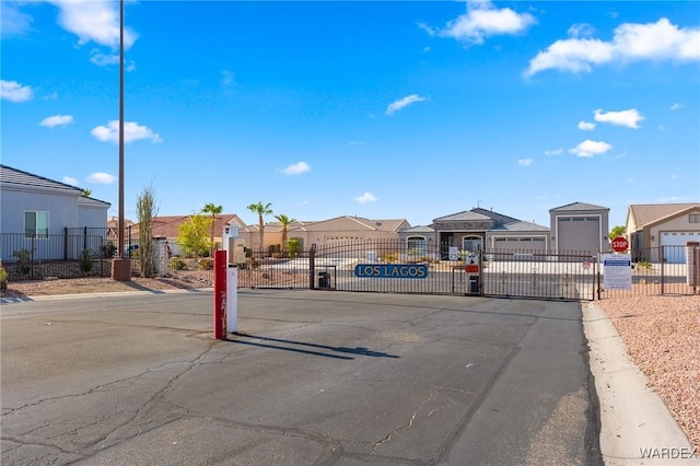 view of street featuring curbs, a gated entry, traffic signs, and a residential view