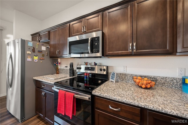 kitchen with light stone countertops, dark brown cabinetry, appliances with stainless steel finishes, and dark wood finished floors