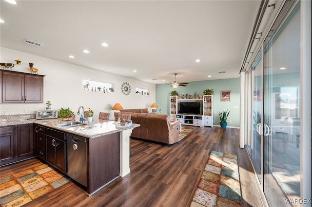 kitchen featuring light stone counters, dark wood finished floors, stainless steel dishwasher, open floor plan, and a sink