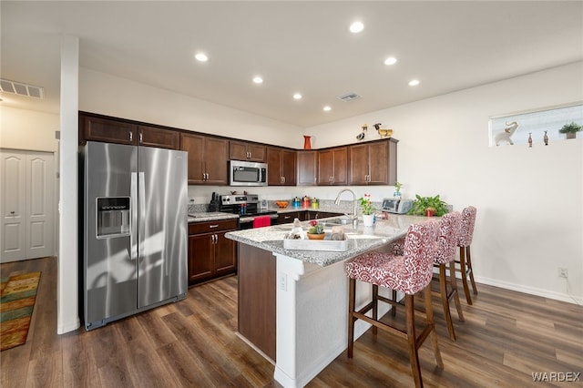 kitchen featuring appliances with stainless steel finishes, visible vents, a peninsula, and a breakfast bar area