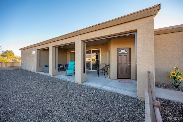 doorway to property with a patio area, fence, and stucco siding