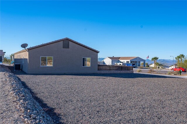 view of home's exterior with central AC unit, fence, and stucco siding