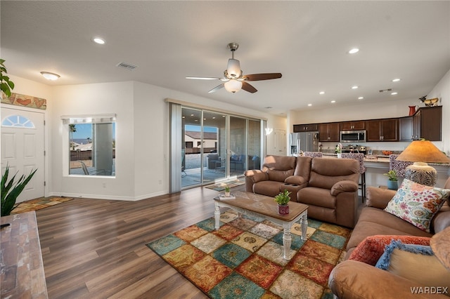 living room featuring recessed lighting, dark wood-style flooring, visible vents, and baseboards