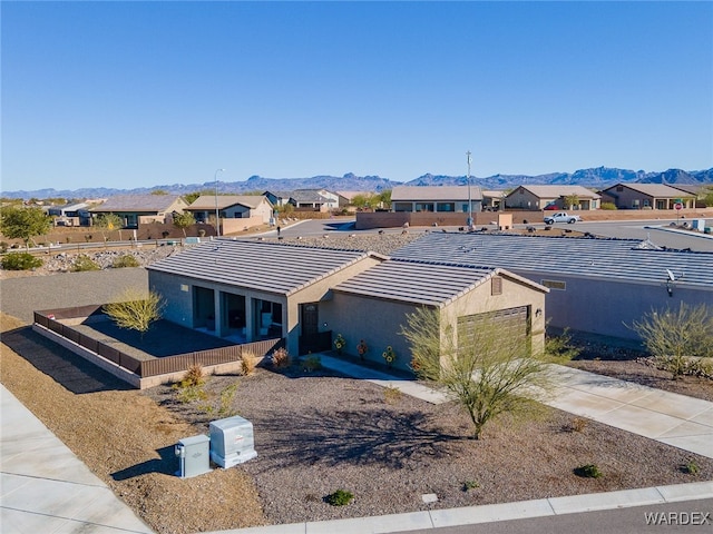 view of front of property with a mountain view, a tile roof, fence, concrete driveway, and a residential view