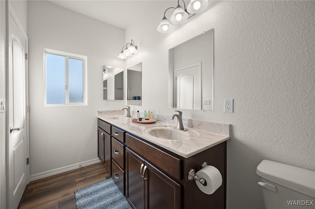 bathroom with toilet, baseboards, a sink, and wood finished floors