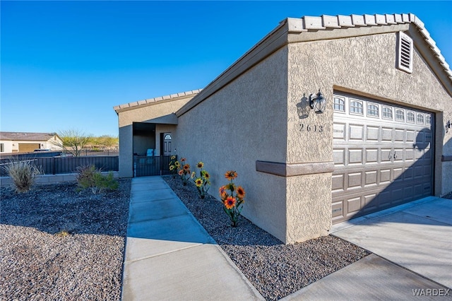 view of property exterior with fence, driveway, and stucco siding