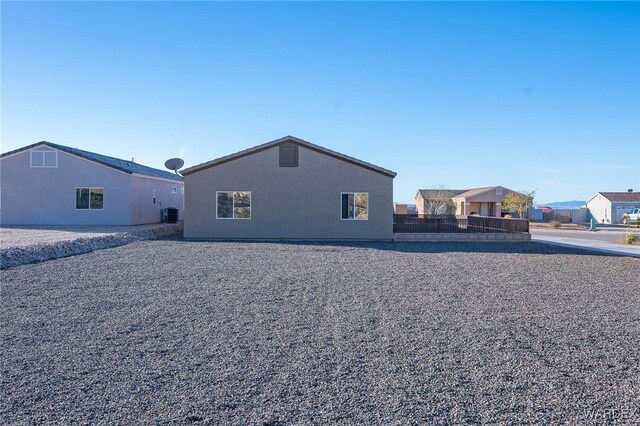 rear view of house with fence and stucco siding