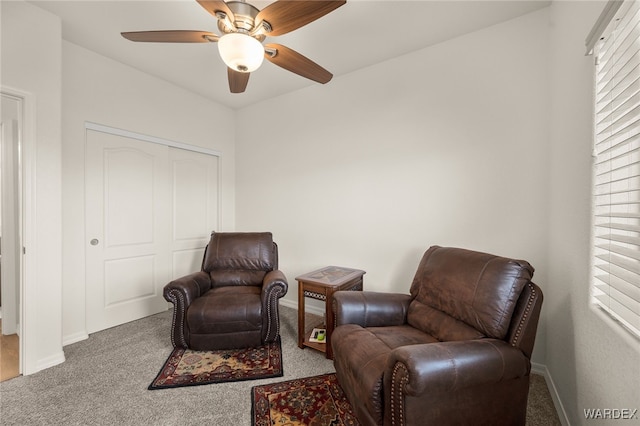 living area featuring ceiling fan, baseboards, and carpet flooring