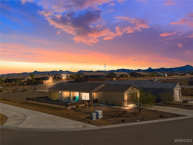 view of front of home with driveway, a garage, a residential view, a tiled roof, and a mountain view